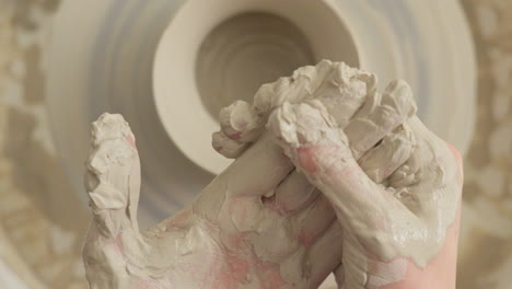 Ceramics-artisan-cleans-his-hands-of-sticky-clay-after-finishing-craft-work-on-the-throwing-wheel