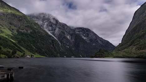 Timelapse-of-a-Naeroyfjord-in-Norway,-stormy-clouds-forming-over-the-mountains,-boats-and-ferries-cruise-fast-as-time-passes