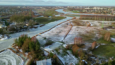 Aerial-Drone-Above-City-at-Outskirts-with-Pale-Blue-River-Water-Frozen-by-Winter