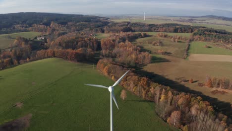 Windkraftanlagen-An-Einem-Sonnigen-Tag-In-Der-Nähe-Des-Dorfes,-Umgeben-Von-Einer-Wiese
