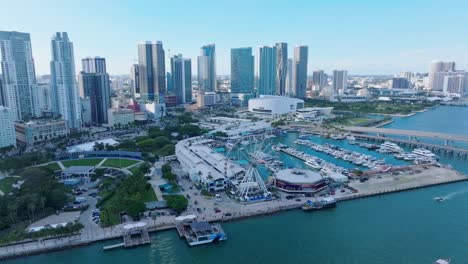 Aerial-establishing-shot-of-Miami-City-Skyline-with-Ferris-Wheel-at-harbor-port-during-sunset-time,-USA