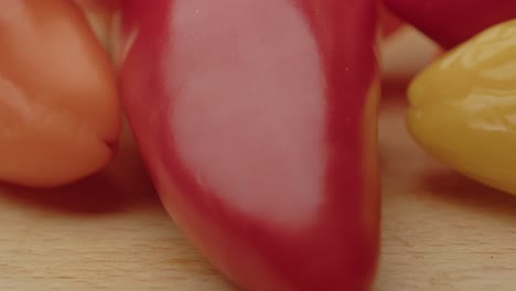 Macro-tilt-up-of-colorful-bell-peppers-on-a-wooden-surface
