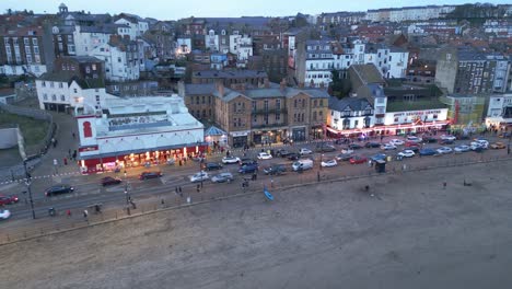 Aerial-drone-panning-shot-over-the-beach-front-in-the-town-of-Scarborough-in-North-Yorkshire,-England-UK-during-evening-time