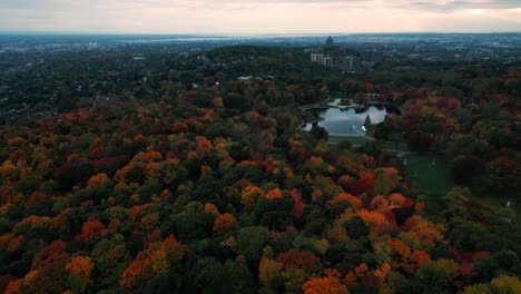 drone-shot-over-Mont-Royal-parc-in-Montreal-during-fall-with-colorful-trees,-lac-aux-castors-and-Saint-Joseph-Oratory-in-the-background