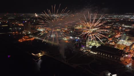 Fireworks-burst-along-Fort-Myers-coast-with-illuminated-city,-Florida-in-USA