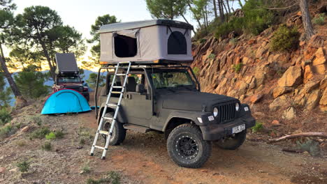 Two-cool-Jeep-4x4-cars-with-rooftop-camping-tents-with-nature-and-green-forest-mountain-view,-fun-outdoors-ATV-adventure-trip-in-Marbella-Malaga-Spain,-4K-shot