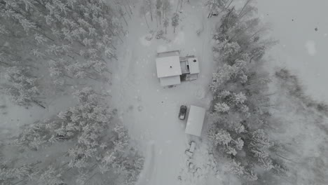 Luftaufnahmen-Aus-Dem-Schnee,-Der-In-Einem-Winterwunderland-Auf-Eine-Hütte-Fällt