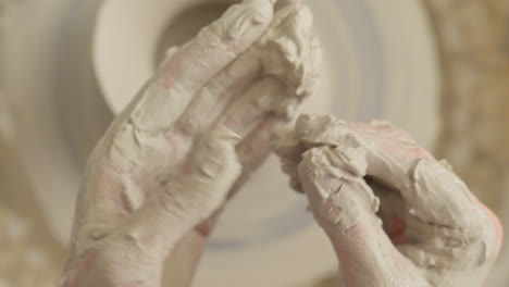 Artist-cleans-his-hands-of-sticky-clay-after-finishing-craft-work-on-the-throwing-wheel
