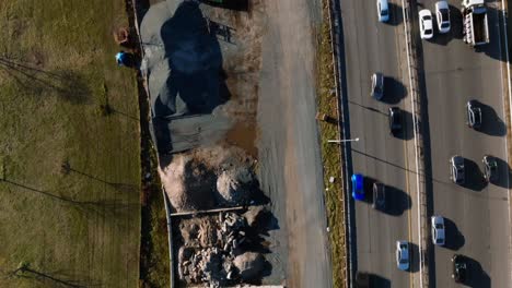 A-top-down-view-over-a-construction-site-with-equipment-and-vehicles-between-the-Belt-Parkway-and-a-park-in-Brooklyn,-NY-on-a-sunny-day