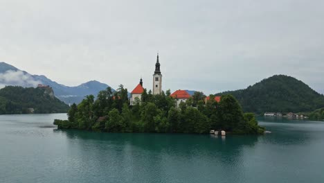 Backward-drone-shot-of-Lake-Bled,-Slovenia-in-the-morning-during-summer-time