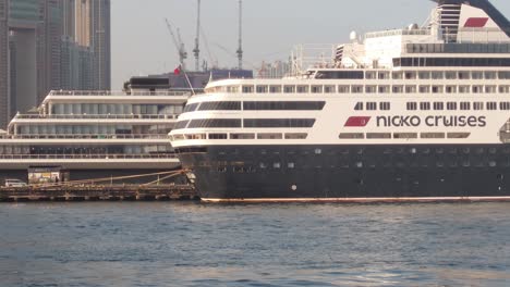 Filmische-Seitenansicht-Eines-Riesigen-Luxuskreuzfahrtschiffs-Tagsüber-Im-Hafen-Von-Tsim-Sha-Tsui-In-Hongkong