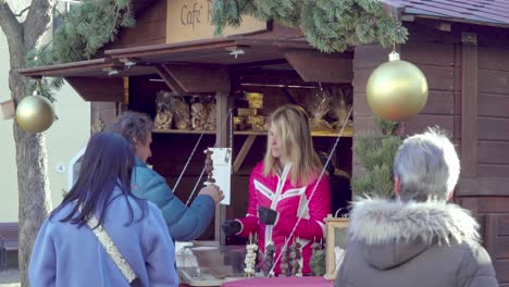 Customers-buying-chocolate-covered-fruit-on-a-stick-at-the-Christmas-market-in-Klausen---Chiusa,-South-Tyrol,-Italy
