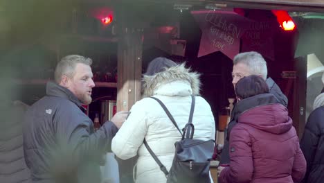 Customers-at-a-Christmas-market-stall-consume-hot-beverages-whilst-having-a-conversation
