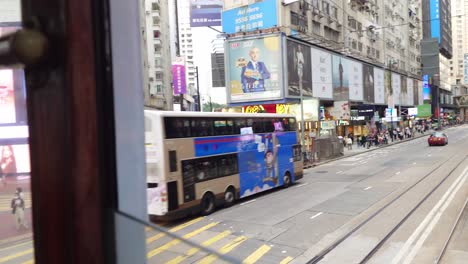 POV-Window-View-From-Back-Of-2nd-Deck-Of-Tram-Driving-Along-Causeway-Bay-Road-Past-Double-Decker-Buses