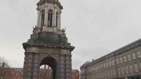 Cinematic-shot-of-Campanile-inside-of-Trinity-College-with-some-students-and-their-parents-during-a-cloudy-day-in-Dublin,-Ireland