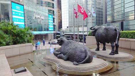 Shot-of-two-statue-of-bulls-and-some-visitors-present-in-front-of-Hong-Kong-Stock-Exchange-Center-during-daytime