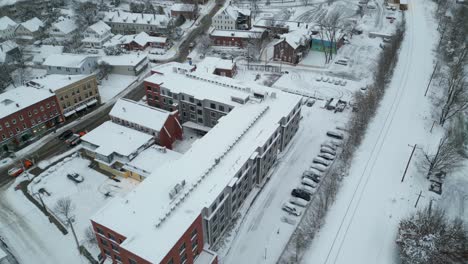 Drone-tilt-up-to-reveal-downtown-main-street-snow-trucks-clearing-roads-after-storm