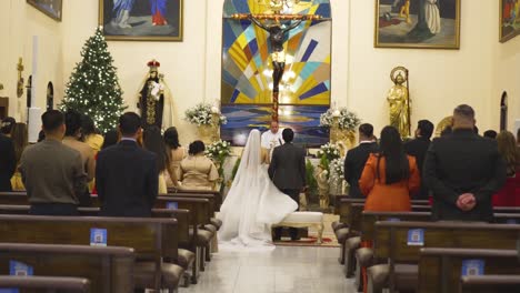 Ceremonia-De-Boda-En-La-Iglesia-Católica,-Joven-Pareja-Latina-Parada-En-El-Altar-Frente-Al-Sacerdote