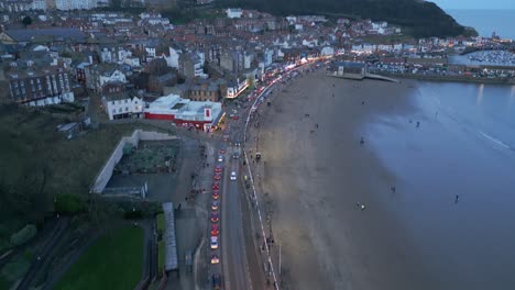 Aerial-drone-tilt-down-shot-over-sandy-beaches-along-the-town-of-Scarborough-in-North-Yorkshire,-England-UK-during-evening-time