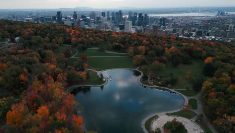 Drone-shot-over-Montreal-city-from-the-parc-Mont-Royal-and-the-"lacs-aux-castors"-during-fall-season-with-the-trees-and-lake-in-the-foreground-and-the-buildings-in-the-background