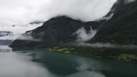 Drohnenaufnahme-Eines-Wasserfalls-Hinter-Einem-Norwegischen-See,-Verdeckt-Von-Wolken
