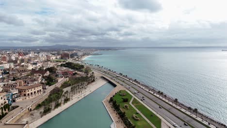 Aerial-flight-over-coastal-Road-of-Palma-de-Mallorca-with-traffic-and-bay-during-cloudy-day,-Spain