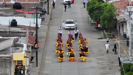Aerial-backwards-shot-of-mexican-dance-group-with-yellow-costumes-on-street-during-Mariachi-Festival-2023-in-Mexico