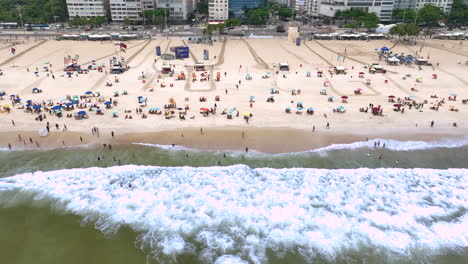 Waves-run-onto-white-sandy-Copacabana-beach-with-sunbathers,-Rio
