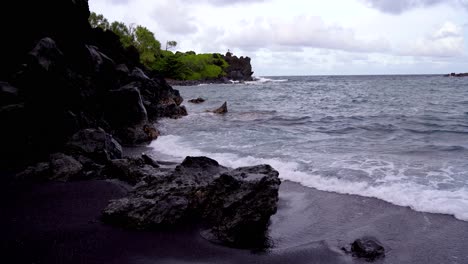 Schwarzer-Sandstrand-Im-Waianapanapa-State-Park-Entlang-Der-Straße-Nach-Hana-In-East-Maui,-Hawaii,-Ein-Beliebtes-Touristenziel-Entlang-Der-Straße-Nach-Hana