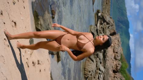 The-beauty-of-a-bikini-clad-model-is-accentuated-in-a-vertical-video-as-she-poses-with-grace-and-allure-on-the-sandy-beach