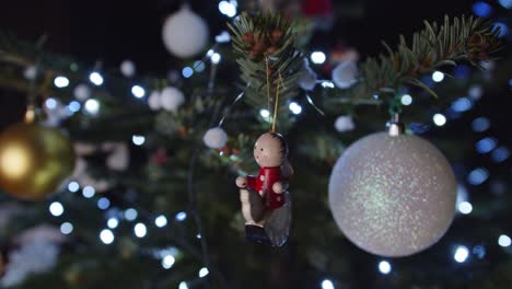 Hängende-Bunte-Spielzeugdekoration-Am-Grünen-Weihnachtsbaum,-Nahaufnahme,-Dunkel-4K