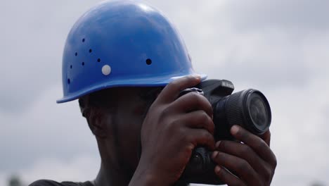 Afrikanischer-Ingenieur-Mit-Blauem-Schutzhelm-Dokumentiert-Den-Bauprozess-Mit-Der-Kamera
