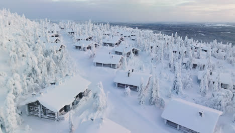 Aerial-view-over-snowy-cabins-on-top-of-a-tunturi-mountain,-polar-night-in-Finland
