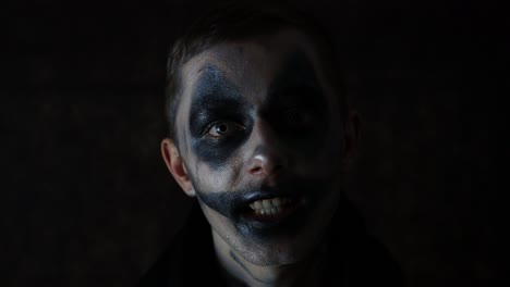 Halloween-Make-up,-Kaukasischer-Mann,-Der-Vor-Einem-Dunklen-Clown-Mit-Gruseligem-Auftritt-Vor-Schwarzem-Hintergrund-Spricht