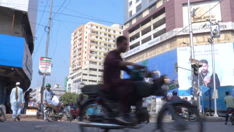 Toma-De-Motocicletas,-Automóviles-Y-Rickshaws-Pasando-Por-La-Calle-Saddar-Bazar-En-Una-Tarde-Soleada-En-Karachi,-Pakistán