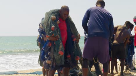 Afrikanische-Menschen-Tragen-Fischernetze-An-Einem-Strand-In-Ghana