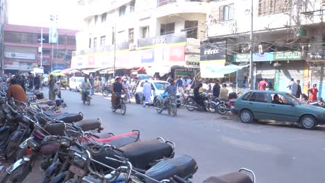 Cinematic-shot-of-busy-Saddar-Bazar-Street-with-motor-cycles-and-cars-parked-at-either-side-of-the-road-in-Karachi,-Pakistan