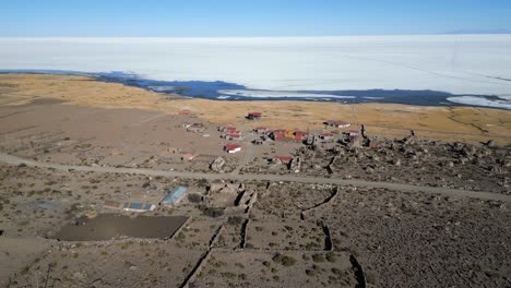 Vuelo-Aéreo-Hacia-Atrás-Desde-La-Aldea,-Salar-De-Uyuni-Al-Fondo,-Bolivia