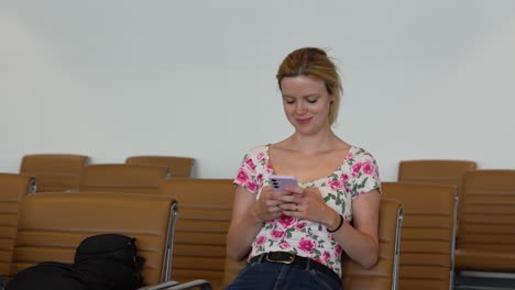 Mujer-Joven-Usando-Un-Teléfono-Inteligente-Mientras-Espera-En-El-Aeropuerto.