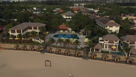 Aerial-tracking-shot-of-allezboo-resort-in-golden-morning-light-featuring-buildings-and-swimming-pool