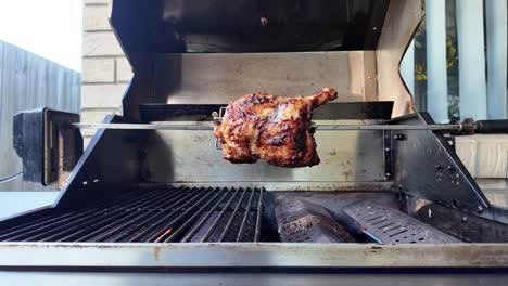 Opening-of-a-BBQ-hood-to-reveal-a-chicken-being-grilled-on-a-rotisserie