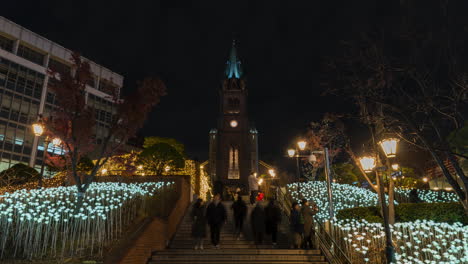 Crowd-of-People-Walking-Up-And-Down-the-Stairs-in-Front-of-Myeongdong-Cathedral-at-Night,-Time-Lapse-in-Seoul,-South-Korea