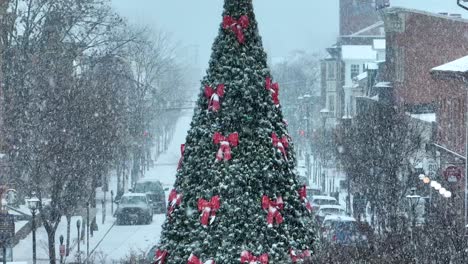 Snowfall-on-a-decorated-Christmas-tree-lined-street-with-historic-buildings