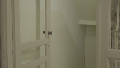 Classic-white-wooden-door-partially-open-to-a-corridor