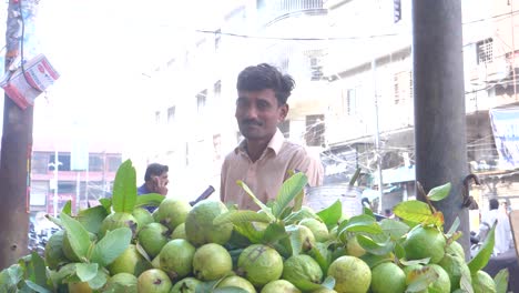 Slow-motion-cinematic-shot-of-a-smiling-shopkeeper-selling-guavas-at-a-roadside-stall-in-Saddar-Bazar-Street-of-Karachi,-Pakistan