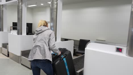 Young-woman-checking-luggage-weight-at-the-airport-counter
