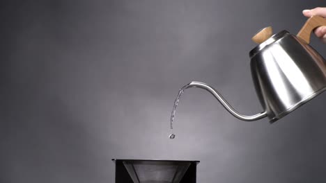 Water-coming-out-of-a-coffeepot-pouring-into-a-pour-over-coffee-maker-in-super-slow-motion