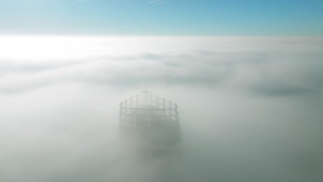 Luftaufnahme:-Drohne-Gleitet-Rückwärts-Und-Enthüllt-Einen-Einsamen-Wolkenkratzer,-Der-Durch-Dichte-Sonnenaufgangswolken-In-Der-Ruhigen-Stadtlandschaft-Auftaucht