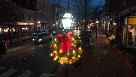 Evening-view-of-a-lit-streetlamp-with-a-festive-wreath-in-a-snow-dusted-Gettysburg-street
