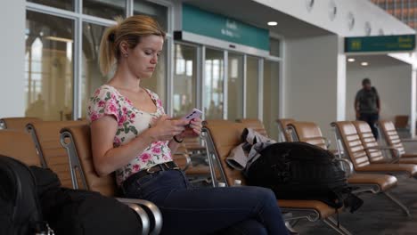 Young-woman-using-her-smartphone,-relaxing-at-the-airport